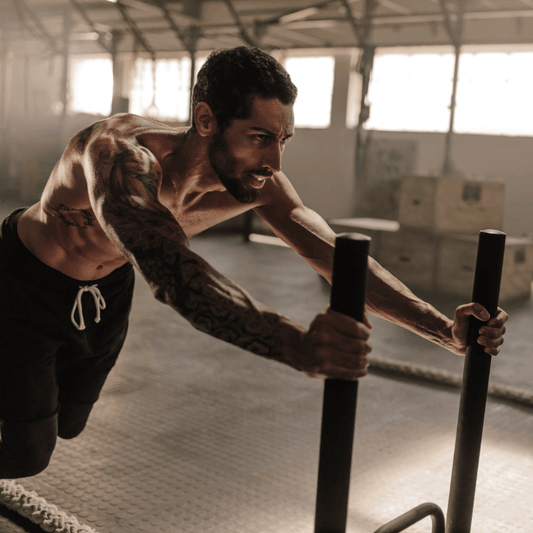 A muscular man pushing a sled in a gym, embodying the power of discipline over motivation in fitness.